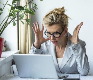 Business woman in a state of shock sitting near the computer.